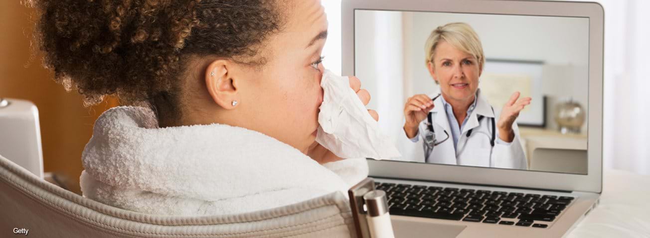 Sick woman video chatting with doctor on laptop