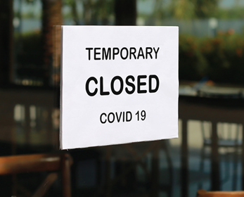 Photo of a restaurant window with a "Temporary Closed COVID 19" sign.