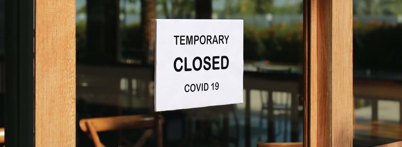 Photo of a restaurant window with a "Temporary Closed COVID 19" sign.