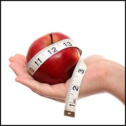 hand holding apple with measuring tape around it