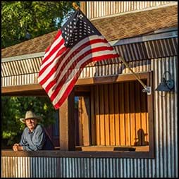 man on porch with american flag
