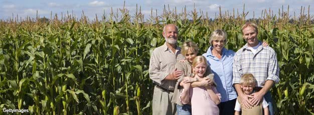 Farm family of three generations by corn field