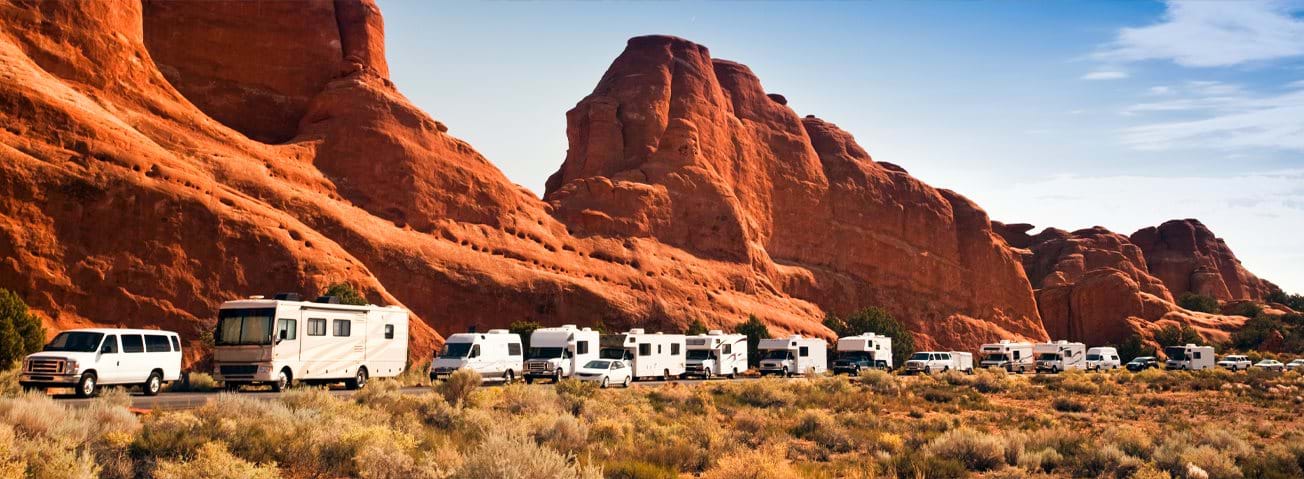 Photo of a line of recreational vehicles with mountains in the background.