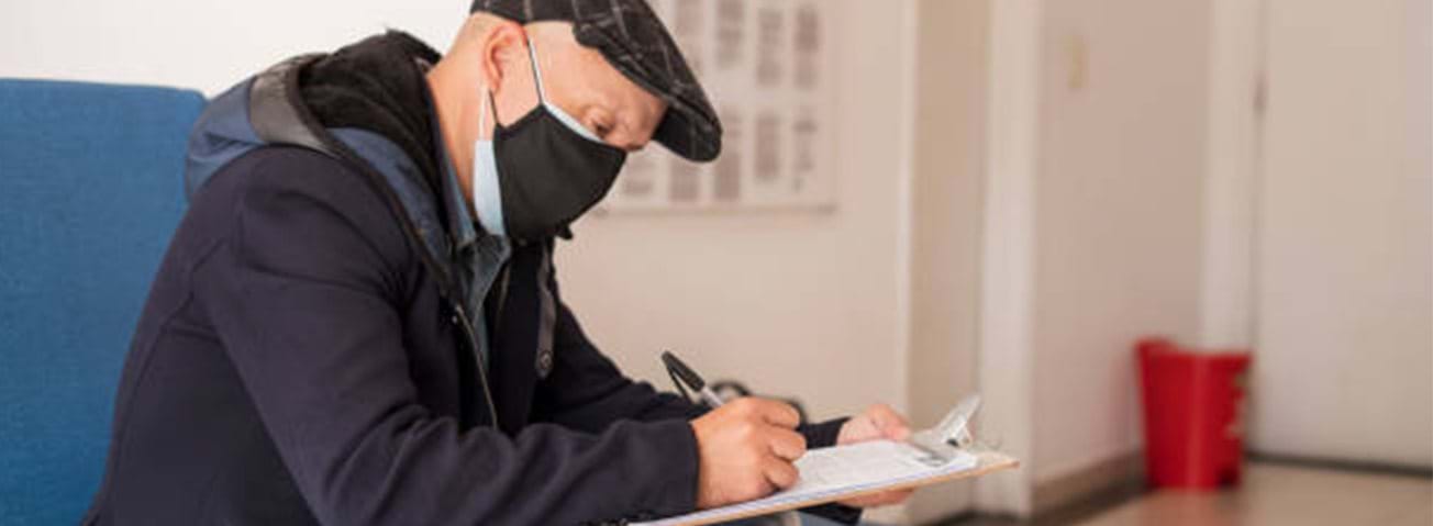 Photo of older man in mask filling out forms