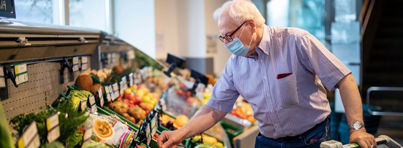 Man in mask shopping in produce department