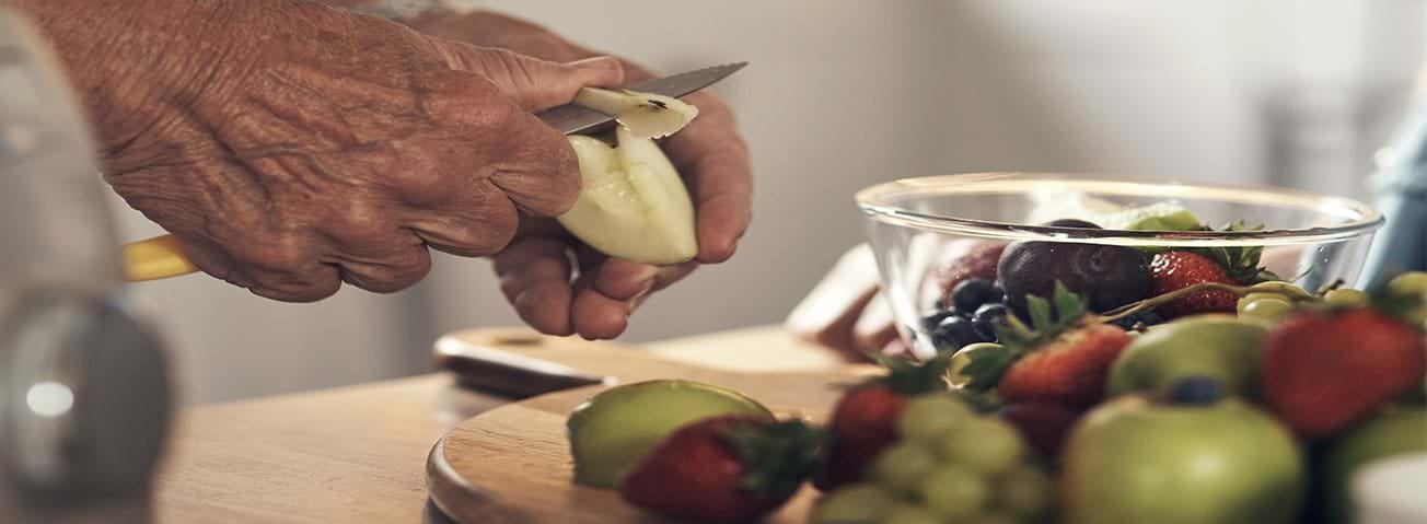 Older hands cutting fruit