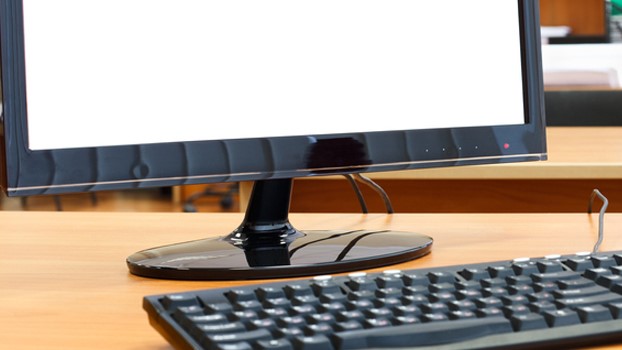 Photo of a computer monitor and keyboard on a desk.