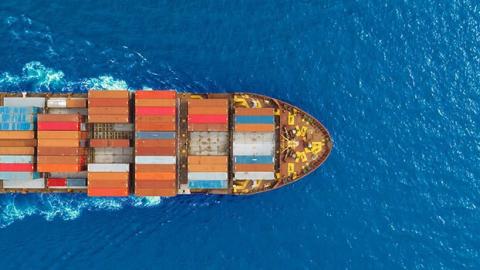 A ship transporting containers across a blue ocean