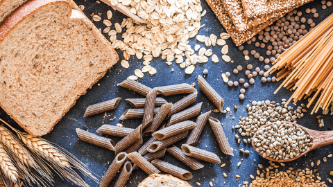 Photo of various whole grain products including bread, crackers, pasta, wheat, oats, and brown rice.